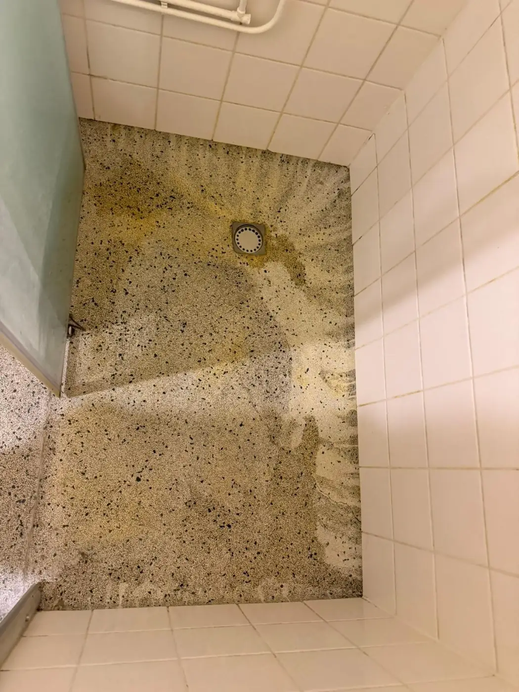 Terrazzo douchevloer voor behandeling — gele aanslag en zeepresten
